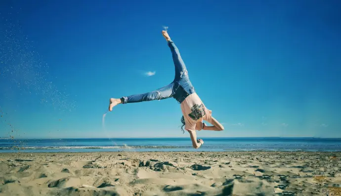 woman in blue denim jeans jumping on beach during daytime